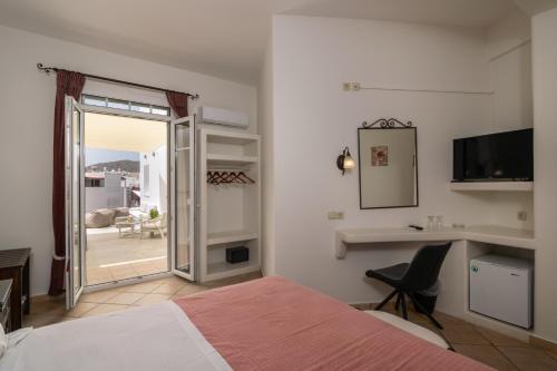 a bedroom with a bed and a desk and a television at Ostria Hotel  in Adamas