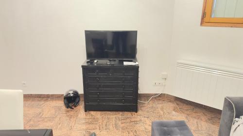 una cassettiera nera con una TV a schermo piatto sopra di Appartement 4 personnes Drancy a Drancy