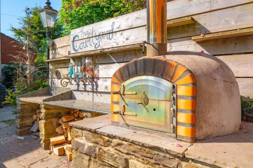 an outdoor pizza oven sitting outside of a building at Luxury Escape with Cinema, Pool Table & Darts in Leeds