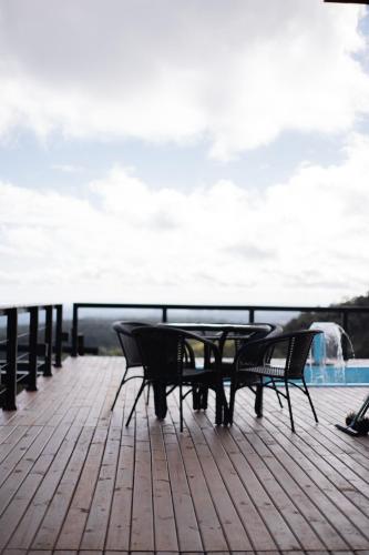 a table and chairs sitting on a deck overlooking the water at Chalé Encantos do Frade in Bom Retiro