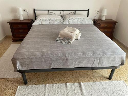 a bed with a gray blanket and two night stands at Budoni -San Pietro in Tamarispa