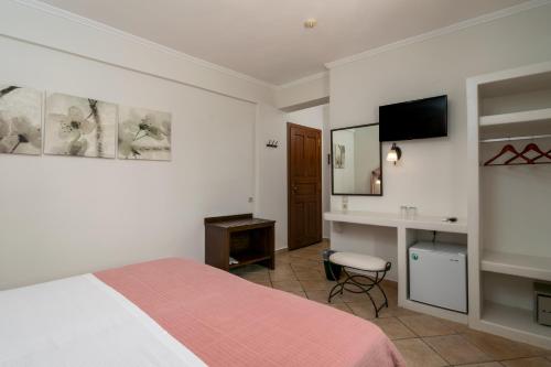 a bedroom with a bed and a desk and a television at Ostria Hotel  in Adamas
