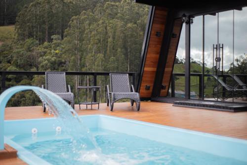 a hot tub on a deck with two chairs at Chalé Encantos do Frade in Bom Retiro