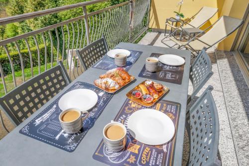 a table with two cups of coffee and food on a balcony at Lake & Whispers - Among Lake Como and Switzerland in San Fedele Intelvi