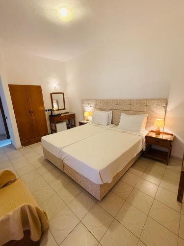 a bedroom with a large white bed and two tables at Asteri Hotel in Livadion