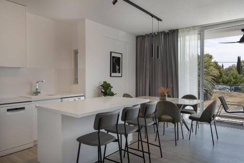 a white kitchen with a table and chairs at Phaedrus Living Travertine Residences 102 in Strovolos