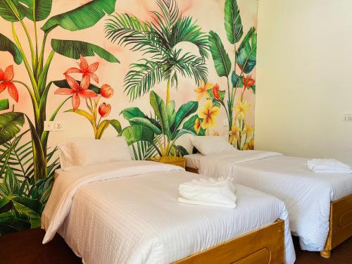 two beds in a room with a tropical wallpaper at Askari Inn Hotels in Swat