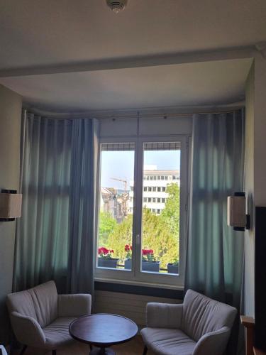 a living room with a large window and a table at Hotel Porta Nigra VICTUS in Trier