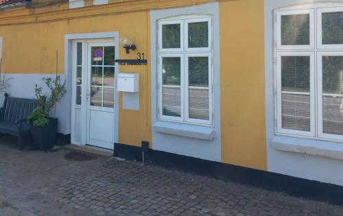 a yellow building with a white door and windows at Villa Sommersted Tanja Blixen in Sommersted