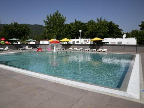 a swimming pool with a fountain with chairs and umbrellas at Camping du Lac in Foix