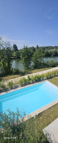 une vue aérienne d'une piscine bleue à côté d'une rivière dans l'établissement Villa Marina, à LʼIsle-Adam