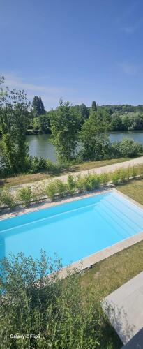 une vue aérienne d'une piscine bleue à côté d'une rivière dans l'établissement Villa Marina, à LʼIsle-Adam