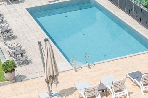an overhead view of a swimming pool with chairs and an umbrella at Gasthof Teiser Stern in Funes
