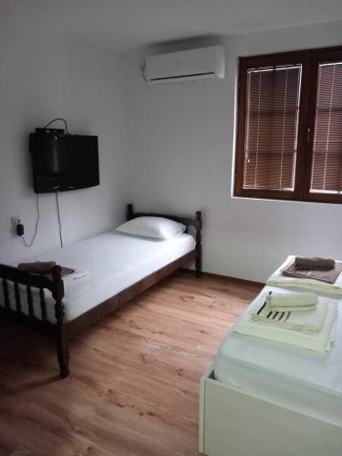 a bedroom with two beds and a tv on the wall at Vila Nika in Veles
