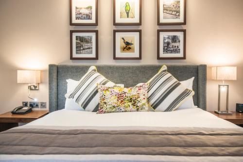 a bedroom with a bed with pillows and pictures on the wall at voco Oxford Thames by IHG in Oxford