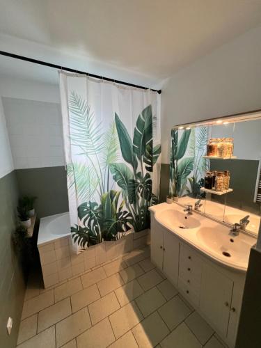 La salle de bains est pourvue de 2 lavabos et d'une grande fenêtre ornée de plantes. dans l'établissement Charmant haut de villa, à Istres