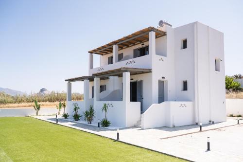 a white house with a lawn in front of it at Filia Skyros Suites in Skiros