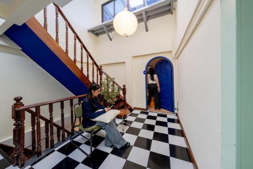 a woman sitting on a chair on a checkered floor at Blue House 191 Hometel in Chinatown