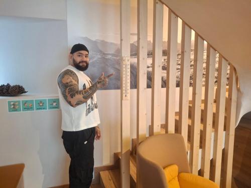 a man with a tattoo on his arm standing next to a staircase at Inner Holiday Dolomites 5 in Dimaro