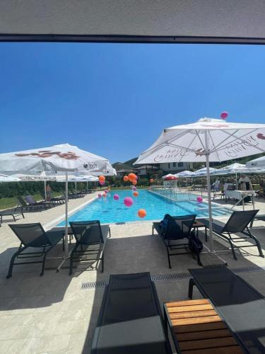 a swimming pool with chairs and umbrellas at Complex YustinaVillas in Ustina