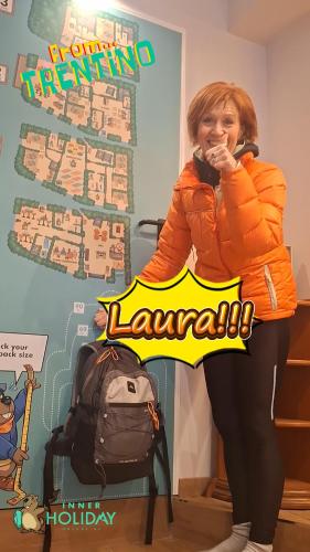 a woman in an orange jacket standing next to a backpack at Inner Holiday Dolomites 5 in Dimaro