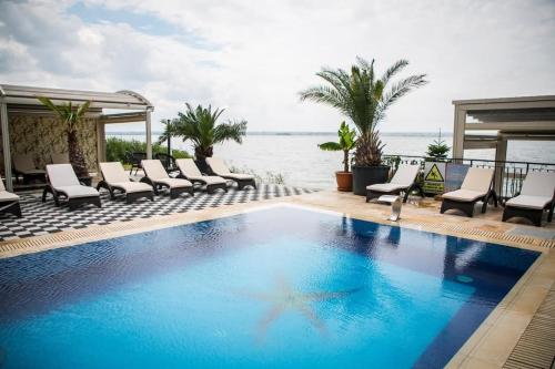 Una piscina con sillas y el océano al fondo. en Almar Lake View Boutique H, en Mamaia