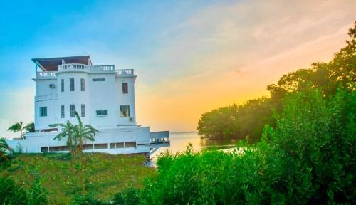 a white building on the shore of a river at See Belize WATERSIDE Sea View Apt for 6 with Kitchen, Balcony, Infinity POOL & Overwater Deck, 2nd Floor in Belize City