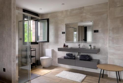 a bathroom with a sink and a toilet and a mirror at Casa con Vistas al Paisaje y Encanto en el Corazón del País Vasco,España in Mungia