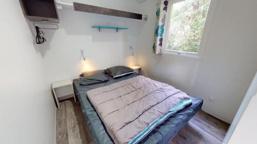 un lit dans une petite pièce avec une fenêtre dans l'établissement Cabane des Dunes, à Saint-Jean-de-Monts