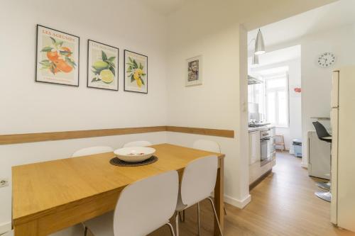 a dining room with a wooden table and white chairs at LV Premier Apartments Baixa- CN in Lisbon