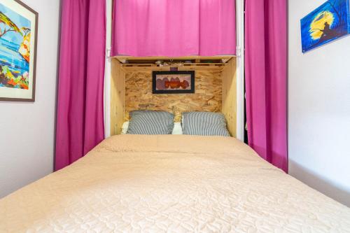 a bed in a room with pink curtains at Appartement Avec Jardin et piscine in Narbonne