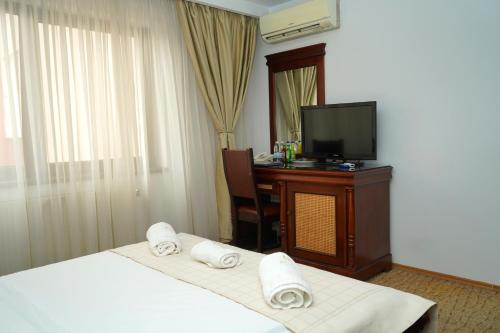 a hotel room with two beds and a television at Hotel Bliss Aksu in Bucharest