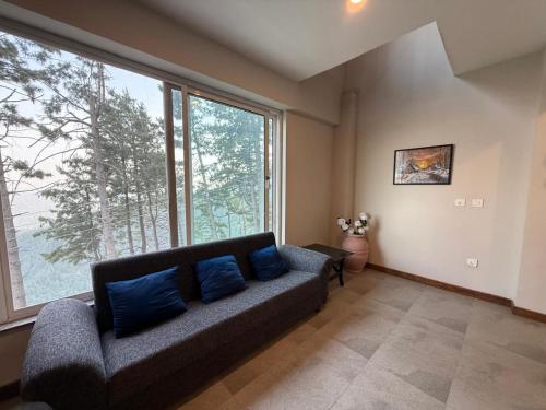 a living room with a couch and a large window at Haven Lodge KhairaGali - Pine Ridge Residences #3 in Khaira Gali