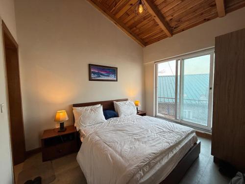 a bedroom with a large bed and a large window at Haven Lodge KhairaGali - Pine Ridge Residences #3 in Khaira Gali
