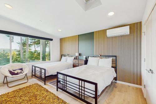 a bedroom with two beds and a chair and a window at Holly Lane Luxe in Gig Harbor