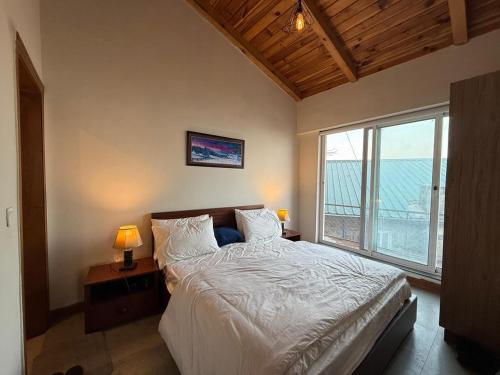 a bedroom with a bed and a large window at Haven Lodge KhairaGali - Pine Ridge Residences #3 in Khaira Gali