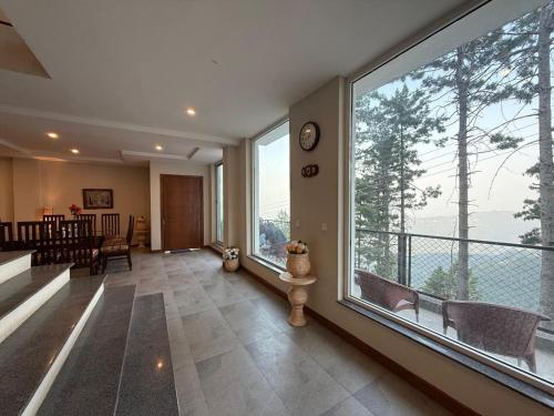a living room with a large window and a dining room at Haven Lodge KhairaGali - Pine Ridge Residences #3 in Khaira Gali