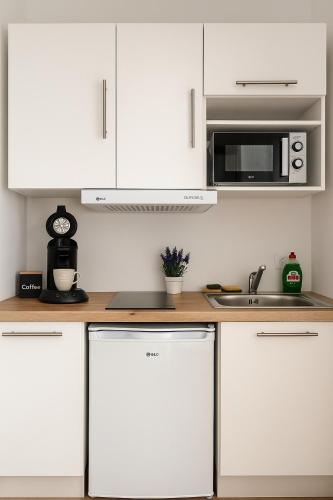 une cuisine avec des armoires blanches et un micro-ondes dans l'établissement Le Nid Cozy à 2 Pas de la Gare St-Dié - Wifi - Calme, à Saint-Dié-des-Vosges