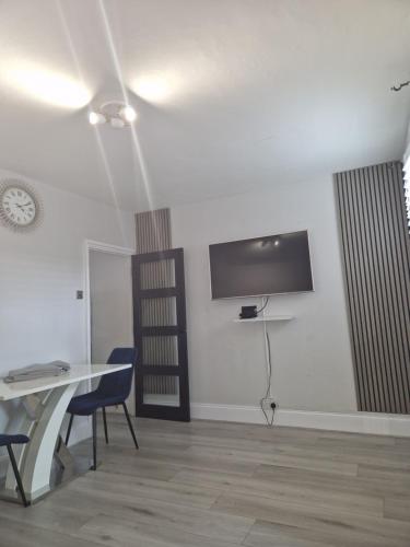 a room with a table and chairs and a tv on the wall at Modern 5 bedroom house with parking, London in Thornton Heath