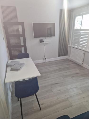 a room with a white table and chairs and a tv at Modern 5 bedroom house with parking, London in Thornton Heath