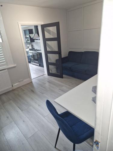 a living room with a table and a blue chair at Modern 5 bedroom house with parking, London in Thornton Heath