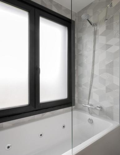 a bathroom with a shower and a bath tub with two windows at Casa con Vistas al Paisaje y Encanto en el Corazón del País Vasco,España in Mungia