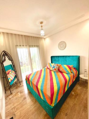 シディ・ラハルにあるSeaside escape beautiful garden apartmentのベッドルーム1室(カラフルな毛布付きのベッド1台付)