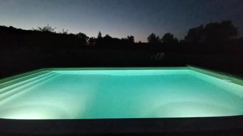 une piscine éclairée la nuit dans l'établissement L'Ecrin du Val de Louyre, à Lentignac