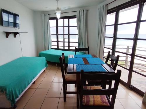 a room with two beds and a table with chairs at Residencial Vila do Sol, Apartamentos com pé na areia in Bombinhas