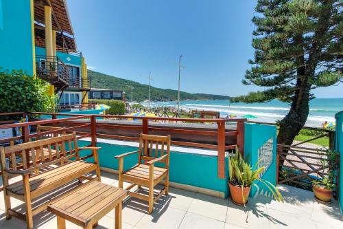 a patio with two benches and a view of the beach at Residencial Vila do Sol, Apartamentos com pé na areia in Bombinhas