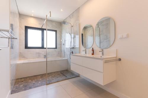 a bathroom with a tub and a sink and mirror at Sapphire Sands by Atlantic Holiday in Estreito da Calheta