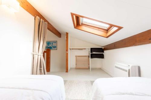 a attic bedroom with two beds and a skylight at Proche lac : Maison avec beau jardin in Biscarrosse