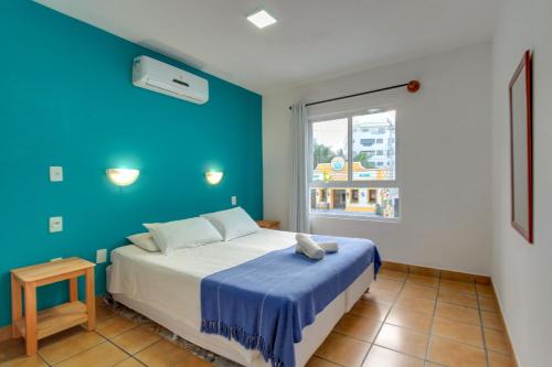 a bedroom with a bed with a blue wall at Residencial Vila do Sol, Apartamentos com pé na areia in Bombinhas