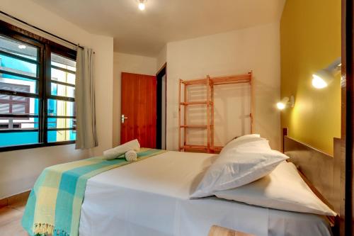 a bedroom with a large white bed and a window at Residencial Vila do Sol, Apartamentos com pé na areia in Bombinhas